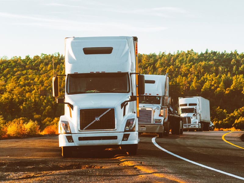 three trucks driving on a forest road