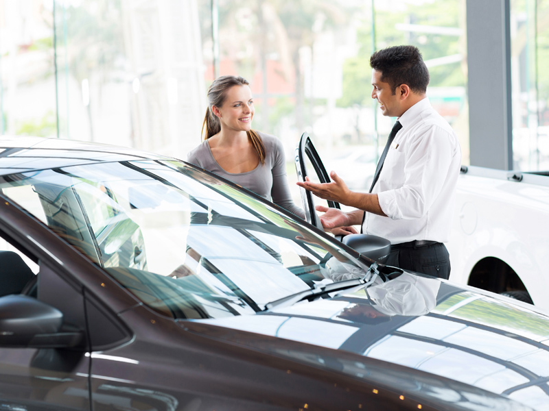 male automotive retailer opening car door for woman