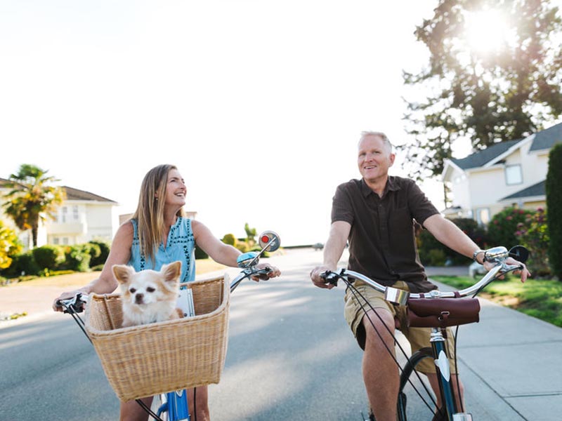 couple riding bikes with dog in basket
