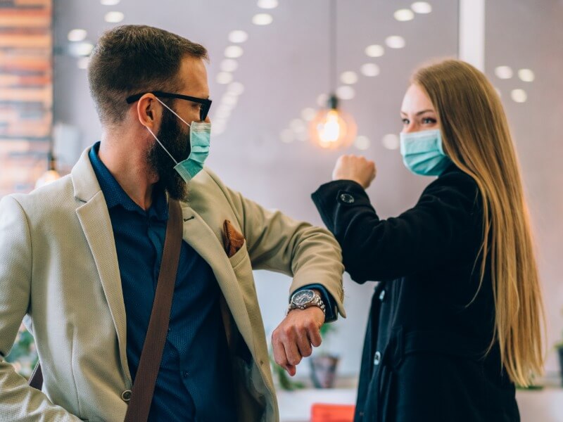 employees wearing masks giving elbow greeting