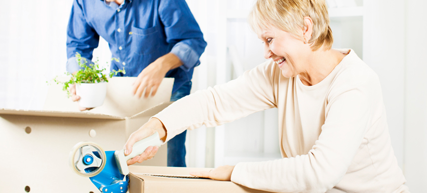 couple packing moving boxes for move to downsized home