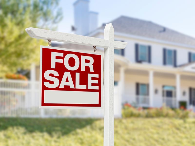 home for sale sign on post outside home