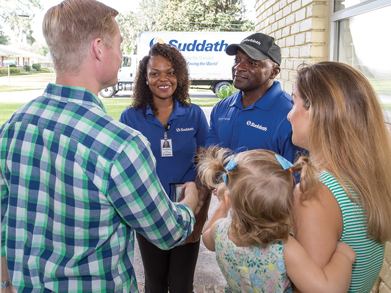 home movers shaking hands with couple at front door