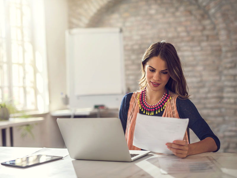 woman at desk with laptop and paperwork