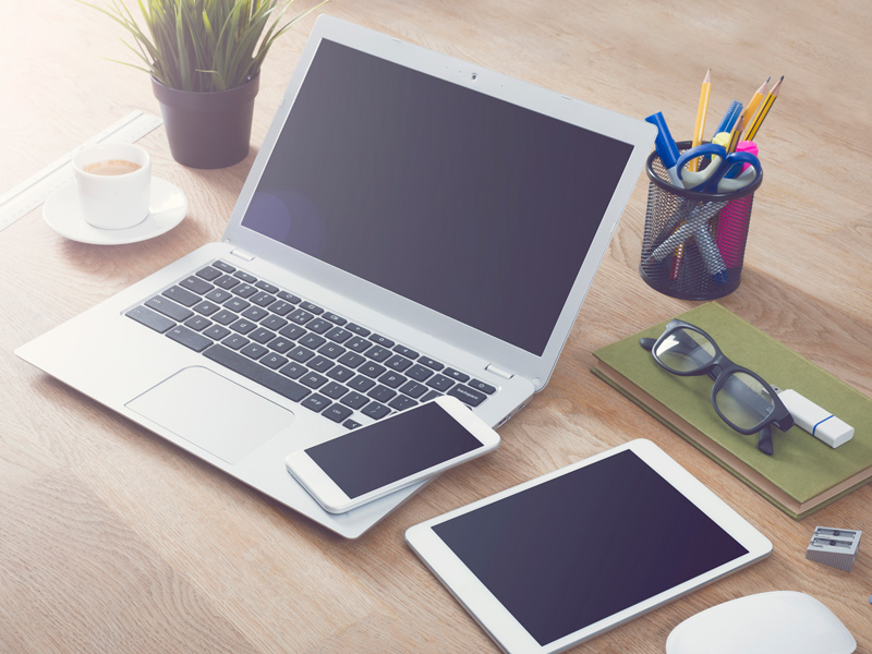 laptop phone and tablet on desk with office supplies