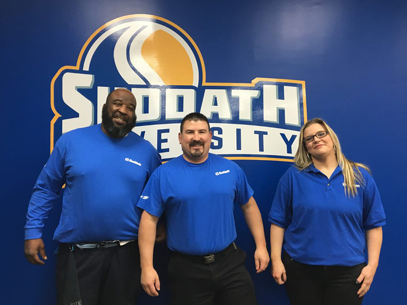 team in front of suddath university sign
