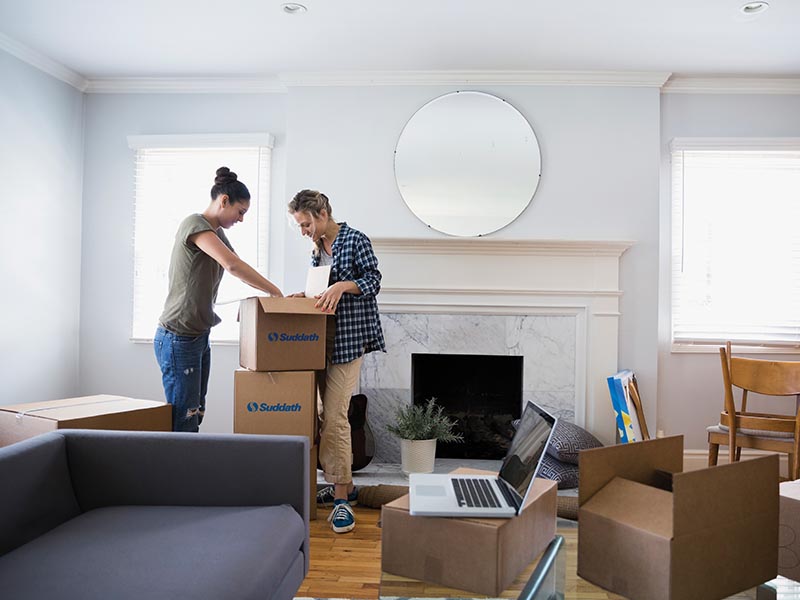 two women packing moving boxes for move
