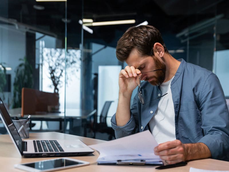 upset businessman reading paperwork at desk office
