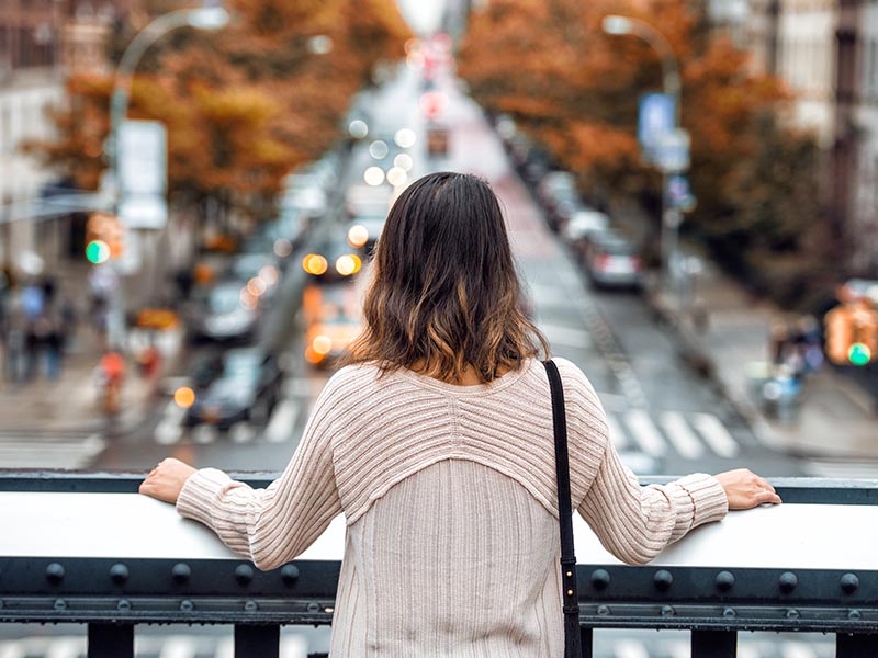 woman on balcony looking down at street